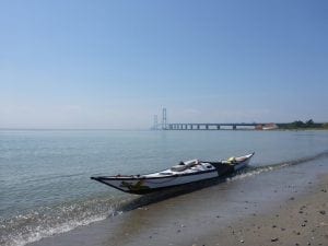 Storebæltsbroen bagved en havkajak på stranden